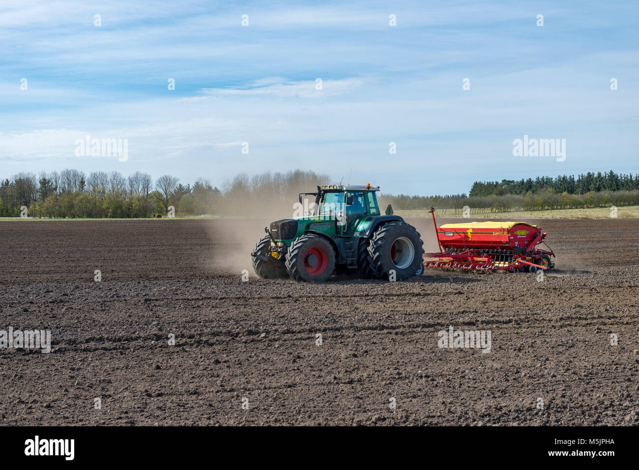 Traktor mit Sämaschine arbeitet ein Feld im Frühling, Län, Dänemark Stockfoto
