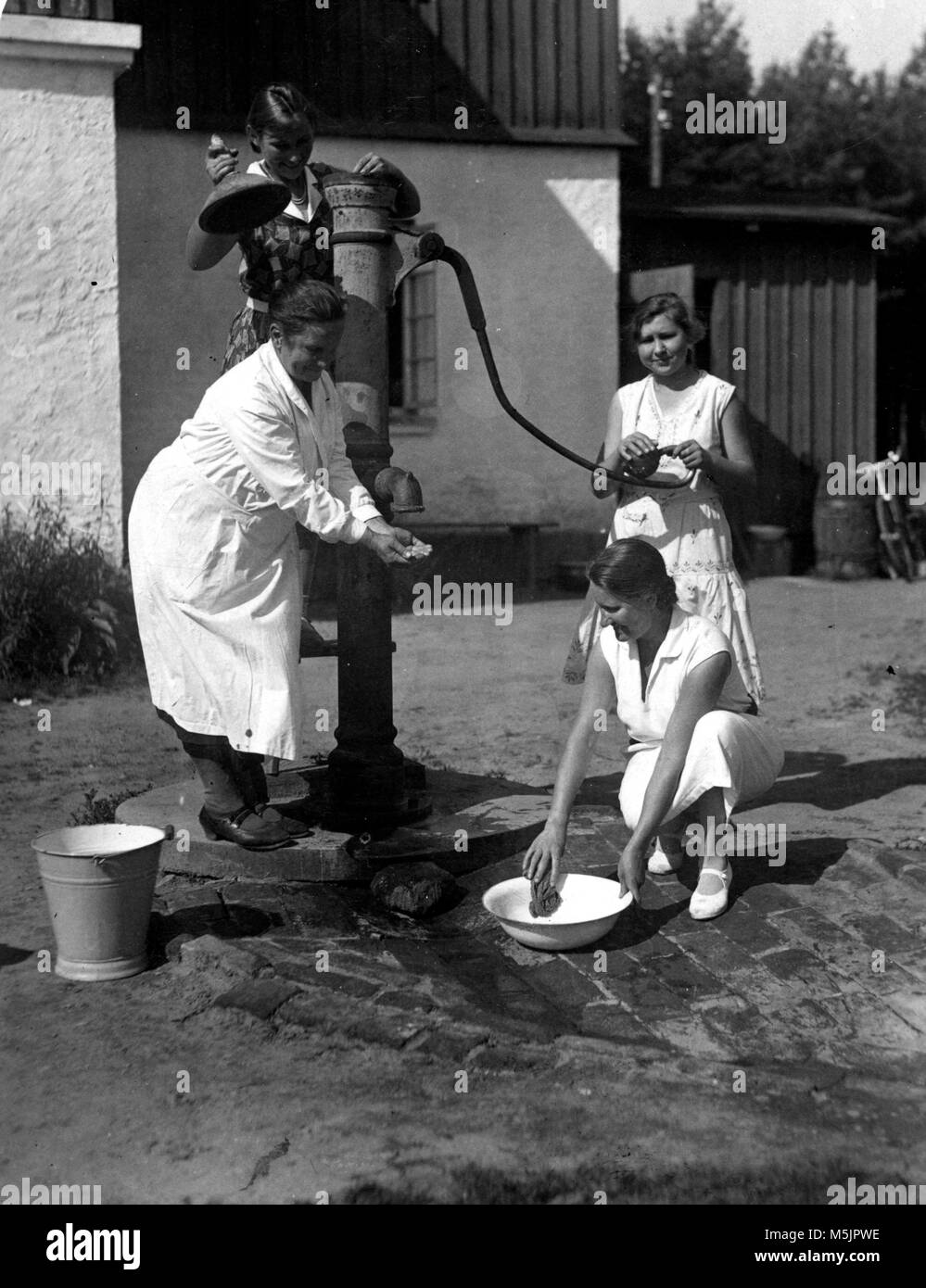 Drei Frauen beim Wasserholen von einer Pumpe, 1920er Jahre, Deutschland Stockfoto