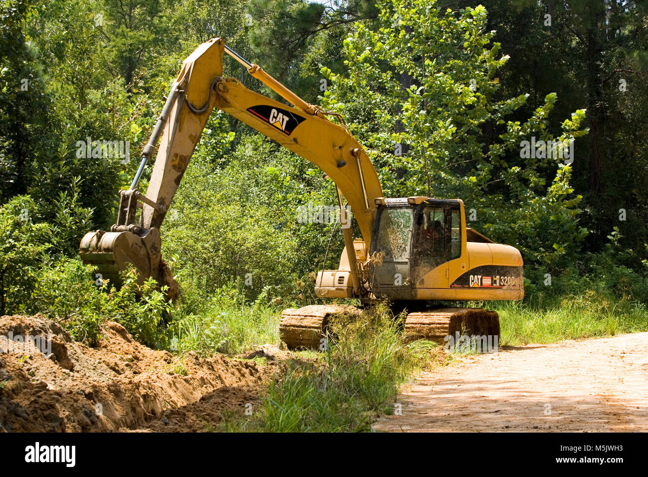 Cat3200 raupenbagger (Spur Hoe, Bagger, mechanische Schaufel) Graben ein Entwässerungsgraben entlang einer Kies Protokollierung Straße in den Alabama River Sumpf, in Clack Stockfoto