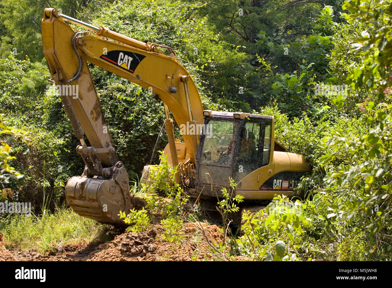 Cat3200 raupenbagger (Spur Hoe, Bagger, mechanische Schaufel) Graben ein Entwässerungsgraben entlang einer Kies Protokollierung Straße in den Alabama River Sumpf, in Clack Stockfoto