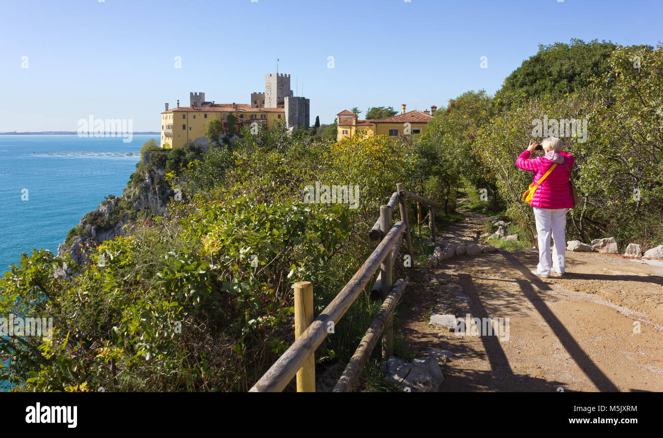 DUINO AURISINA, Italien - 23. Oktober 2017: eine Frau Fotos das Schloss von Duino, an den Klippen der felsigen Küste in der Nähe von Triest, Italien Stockfoto