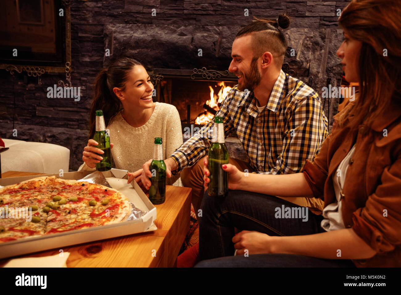 Lächelnde Menschen in legere Kleidung essen Pizza und Bier trinken. Stockfoto