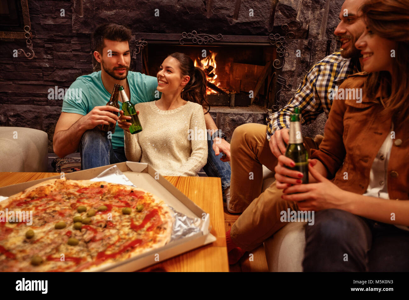 Freizeit, Essen und Trinken und Personen Konzept - lächelnd Freunde essen Pizza und Bier trinken. Stockfoto