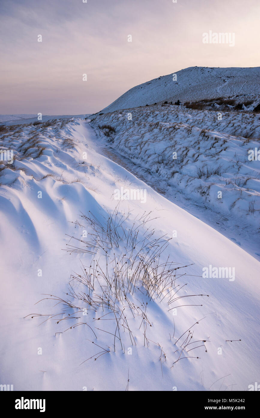 Schneereiche Winter morgen in den Hügeln des Peak District. Schneeverwehungen neben dem Reitweg in South Head, Hayfield, Derbyshire, England. Stockfoto