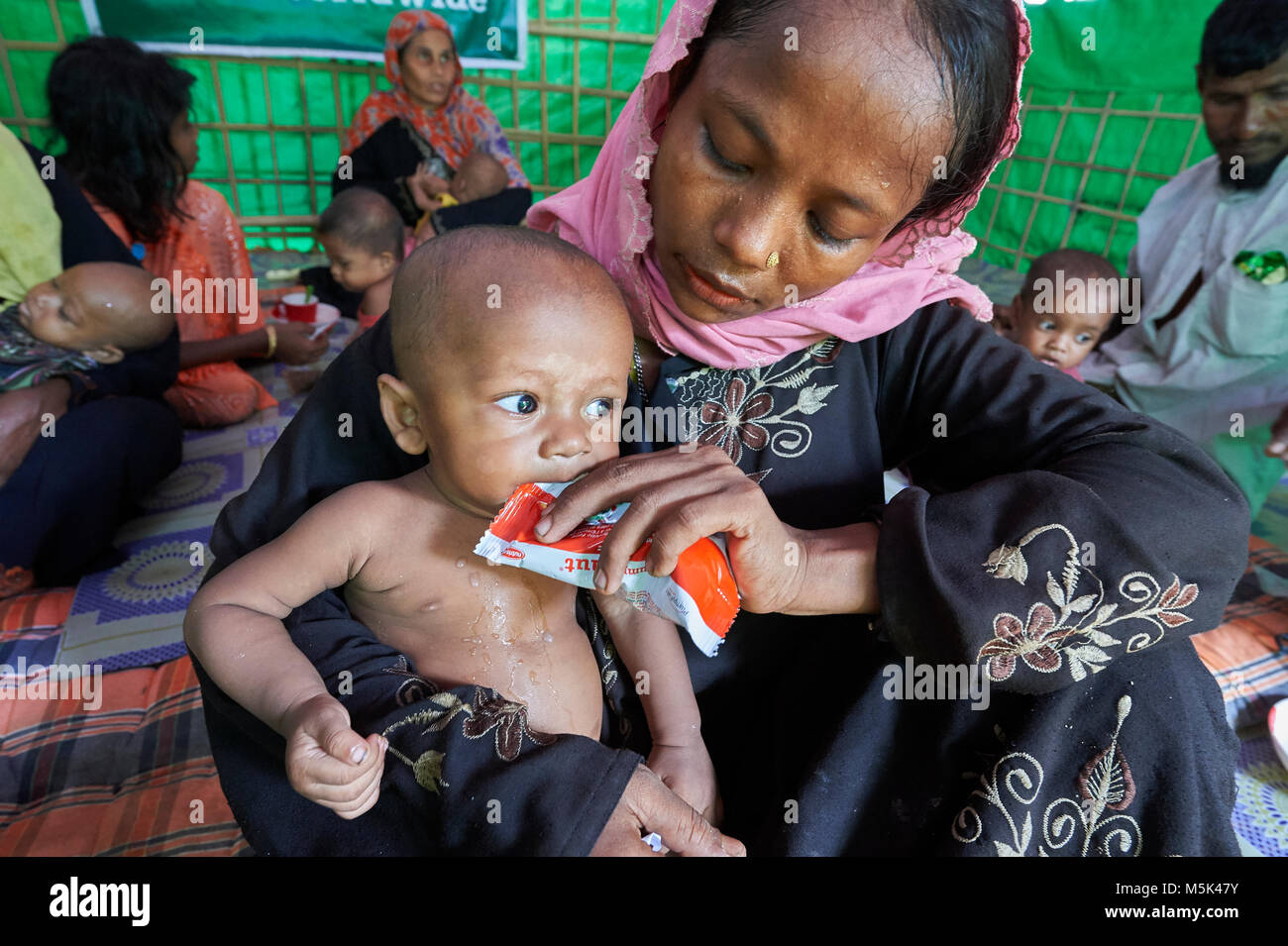Shortly after they made the perilous crossing from Myanmar into Bangladesh, a woman feeds her child in a United Nations clinic for malnourished kids. Stockfoto