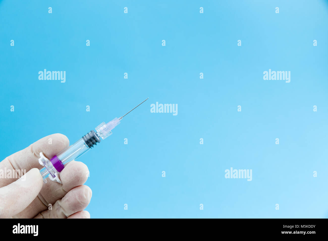 Kanüle mit Grippe Impfstoff oder Medikament in Ärzte Hände medizinische Handschuhe in Weiß auf blauem Hintergrund Kopie Raum isoliert, Studio Shot Stockfoto