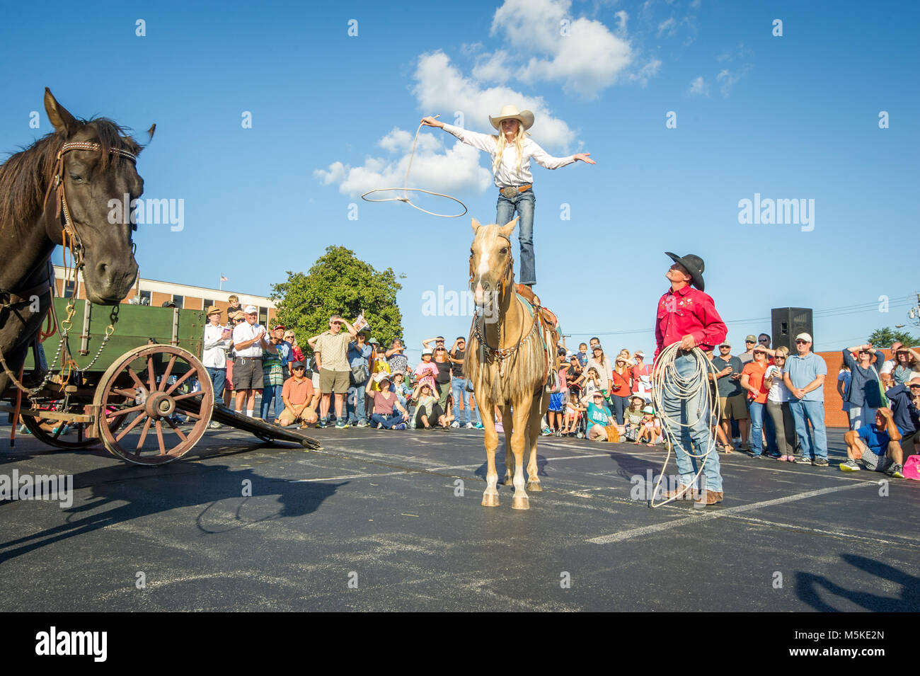 Mann in cowboyhut Uhren junge Mädchen auf Pferd stehen und Vorformen Rope Trick mit Masse beobachten, Greensboro, North Carolina. Stockfoto