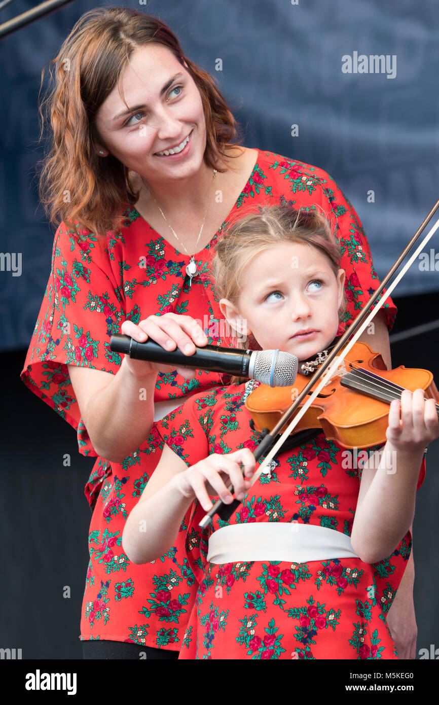 Mutter hält Mikrofon für Tochter, als sie ihre Geige auf der Bühne für Pan Franek, Zosia und die Polka Towners, National Folk Festival, Grün spielt das Leben Stockfoto