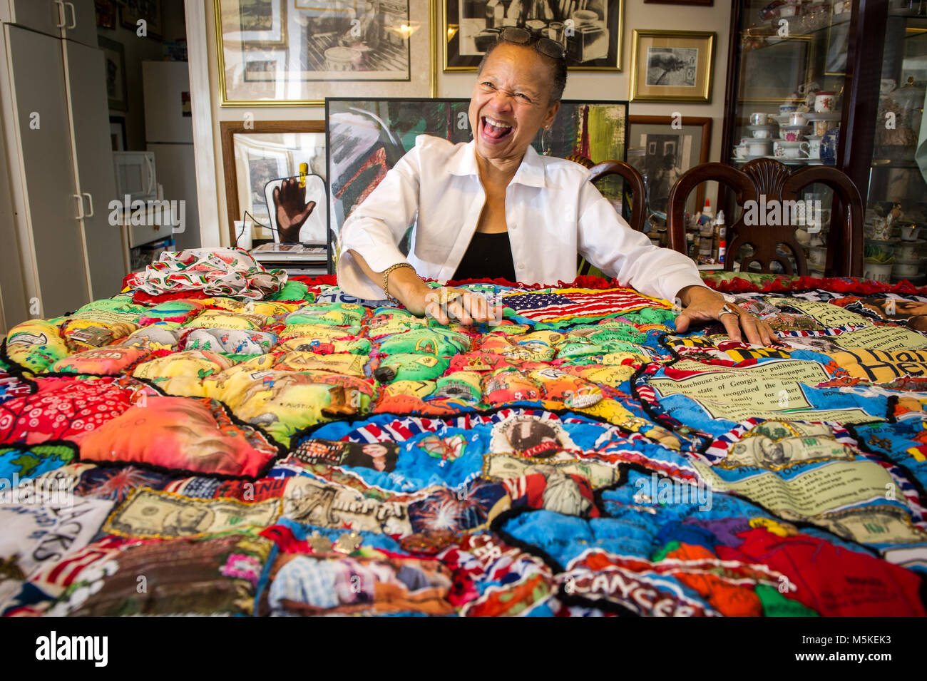 Quiltmaker Joan Gaither sitzt in ihrem Haus freudig lachend mit einem Ihrer Kunsthandwerk heraus vor ihr, Severn, Maryland. Stockfoto