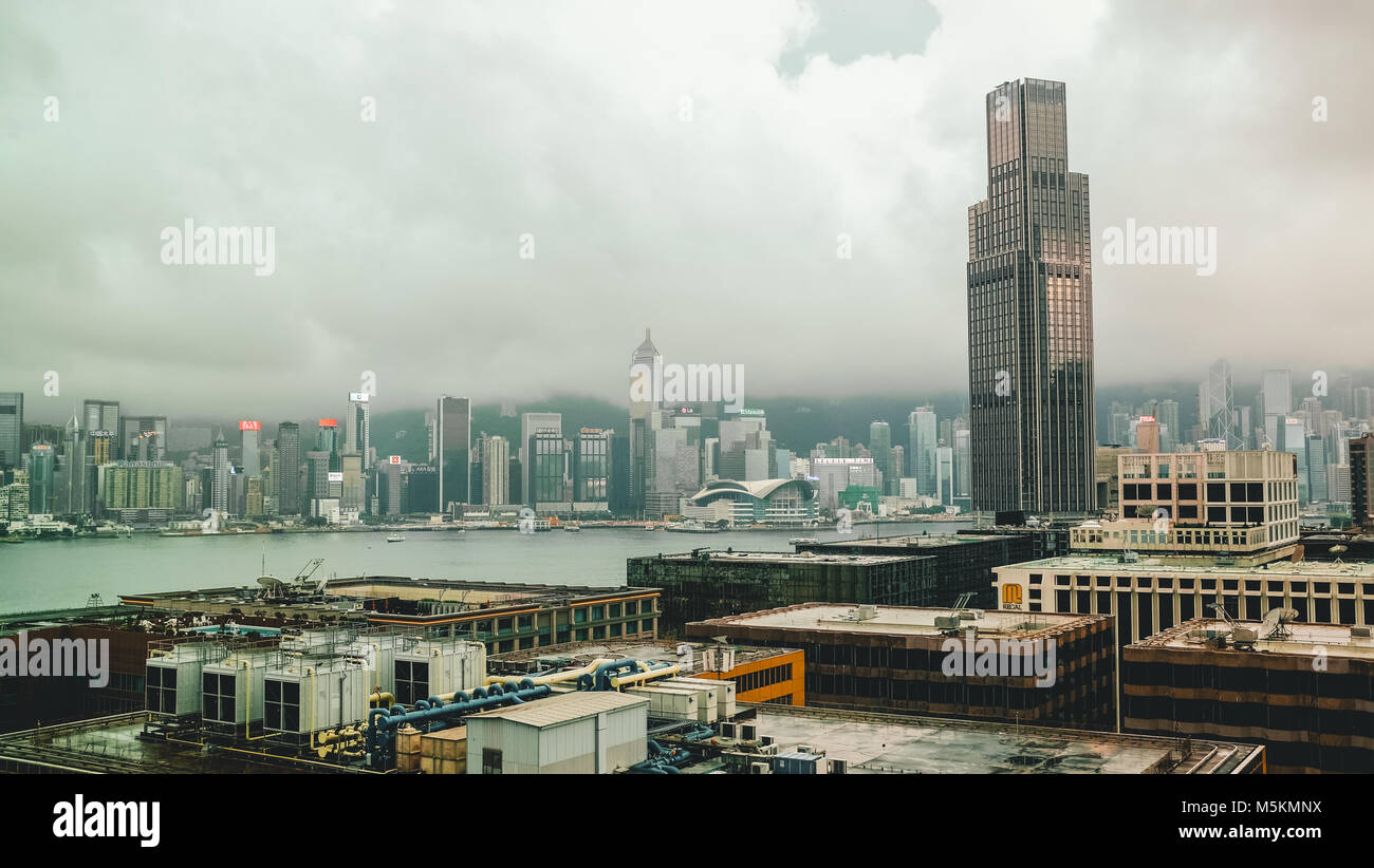 Eine Frau touristische schaut aus Ihrem Hotelzimmer im Hotel Icon an der Skyline von Kowloon, Hong Kong an einem bewölkten Tag Stockfoto