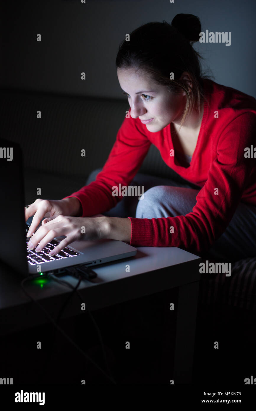 Junge Frau auf ihrem Laptop spät in der Nacht - tief in die Nacht, die versucht, ihr Papier zu beenden Stockfoto