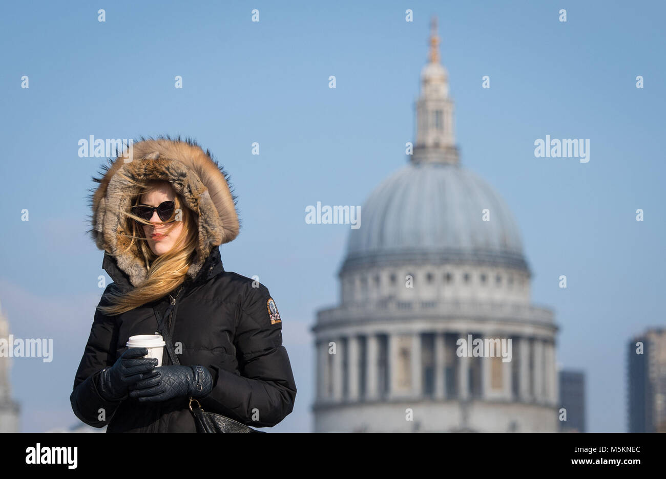 Eine Frau geht über die Millennium Bridge, in London, in windigen Bedingungen wie Einfrieren Luft aus Russland ist zu Griff Großbritannien in welcher Satz ist der kälteste Ende Februar in fünf Jahren sein. Stockfoto