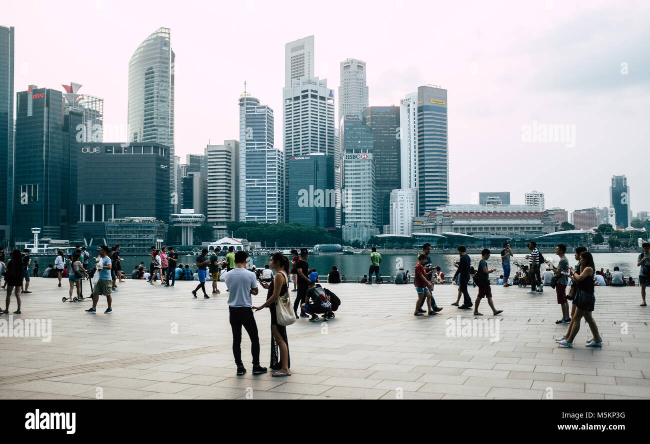 Touristen an der Waterfront in der Marina Bay und die Skyline von Singapur Suchen mit all den hohen Gebäuden von Hotels, Wohnungen und Büros. Stockfoto