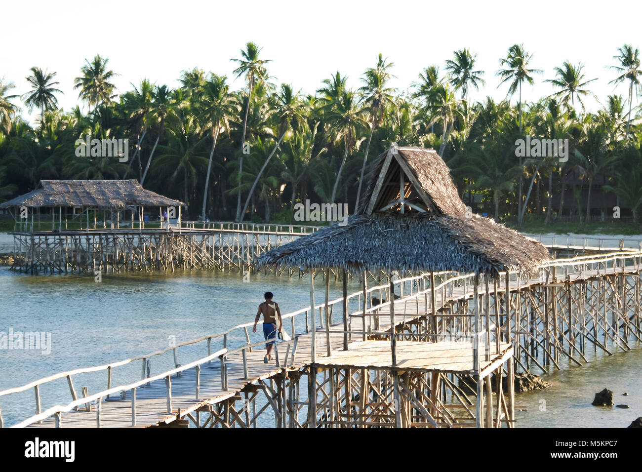 Filipino Surfer sein Surfbrett Durchführung von Wolke 9 surf Pause über das Riff auf der erhöhten Plattform Stockfoto