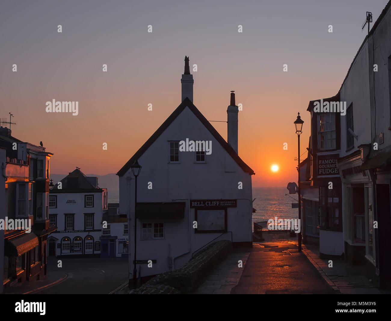 Die Sonne zwischen zwei Gebäuden in der Küstenstadt Lyme Regis. Stockfoto