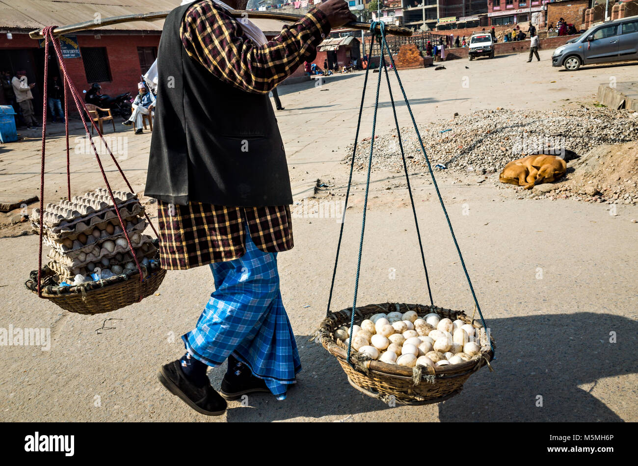 Einem Straßenhändler Wanderungen von Tür zu Tür Verkauf von Eiern in Bambus Korb in der Straße von Kathmandu, Nepal Stockfoto