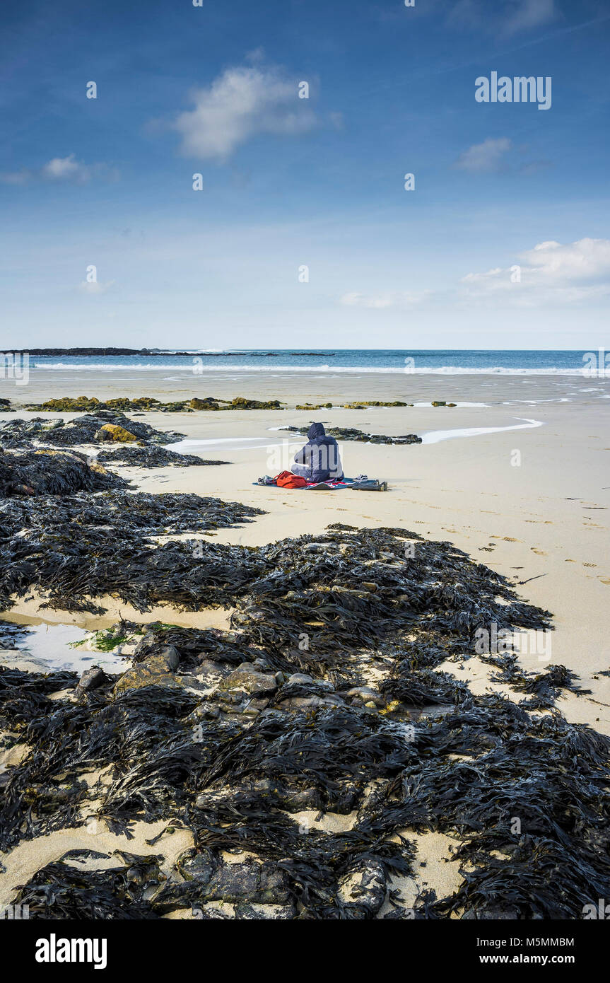 Eine geheimnisvolle Gestalt sitzen am Strand von Sennen Cove in Cornwall. Stockfoto