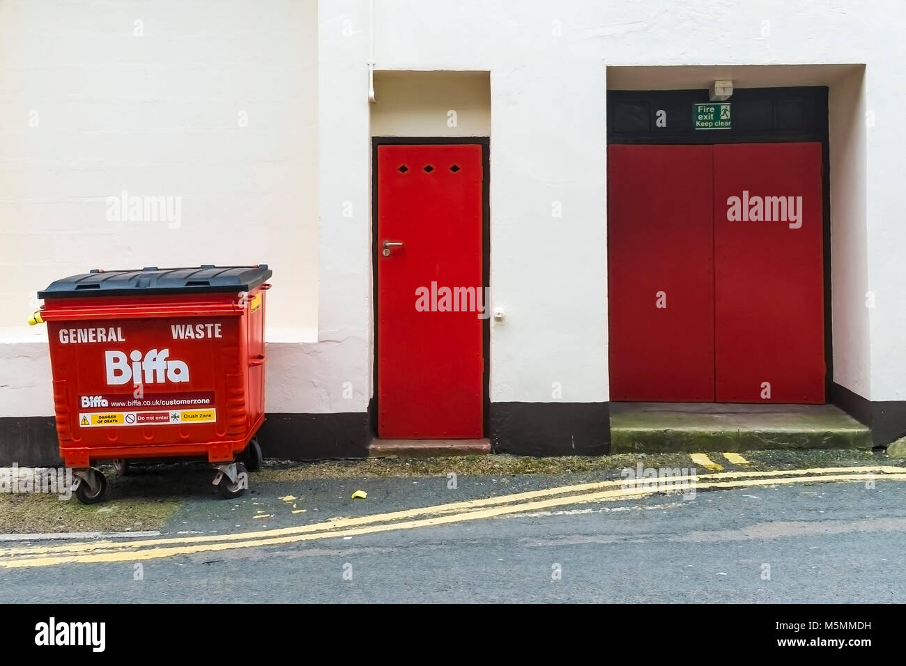 Zwei rote Türen und einem roten Biffa kommerzielle Abfallbehälter. Stockfoto