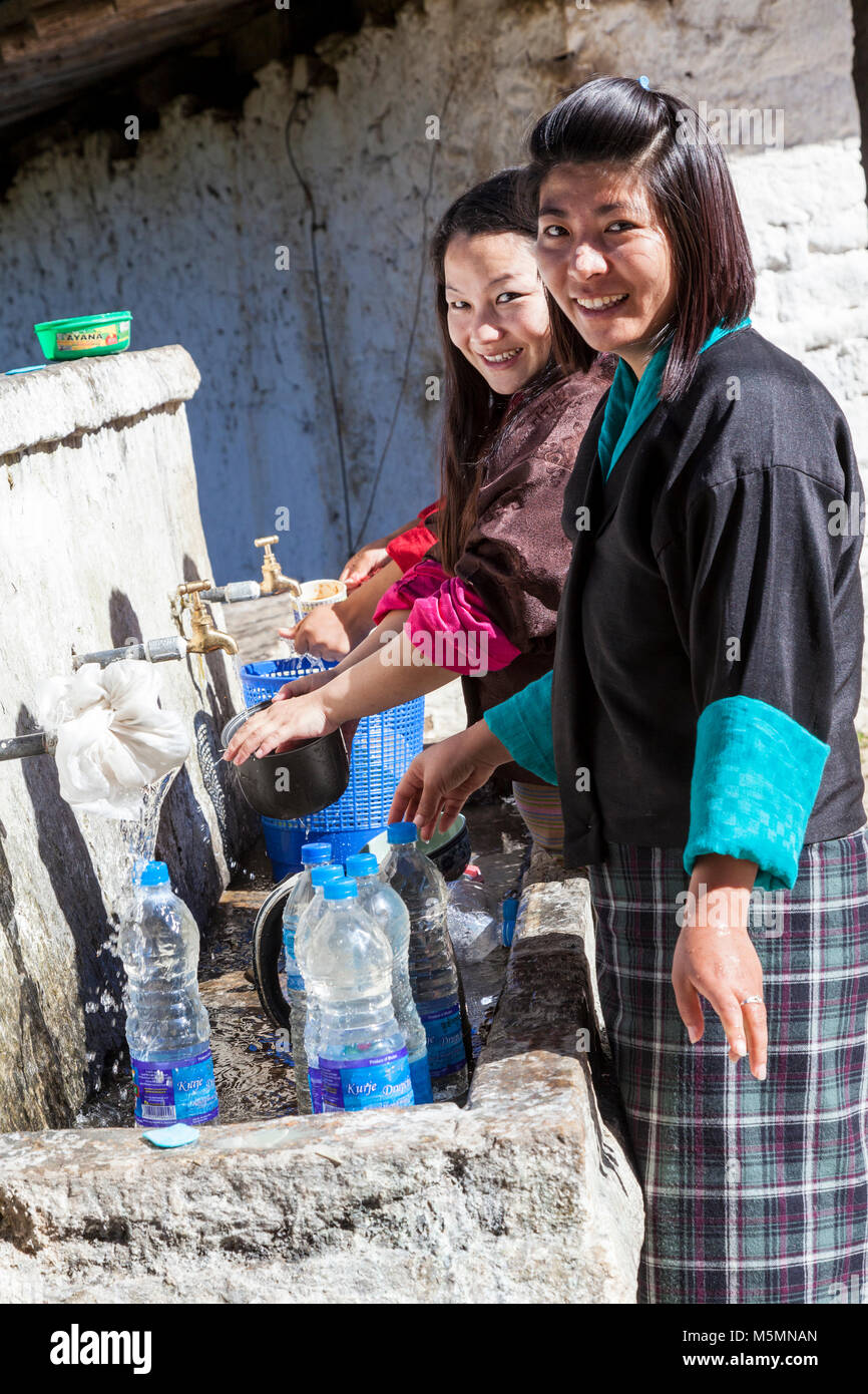 Trongsa, Bhutan. Bhutanesische Frauen Wasser beim Füllen Krüge auf den Wasserhahn in der Trongsa Dzong (Monastery-Fortress). Stockfoto