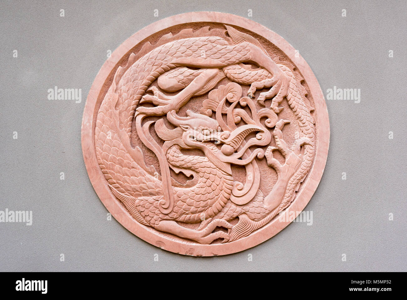 Rote kreisförmige dragon Flachrelief auf eine graue Wand, China Stockfoto