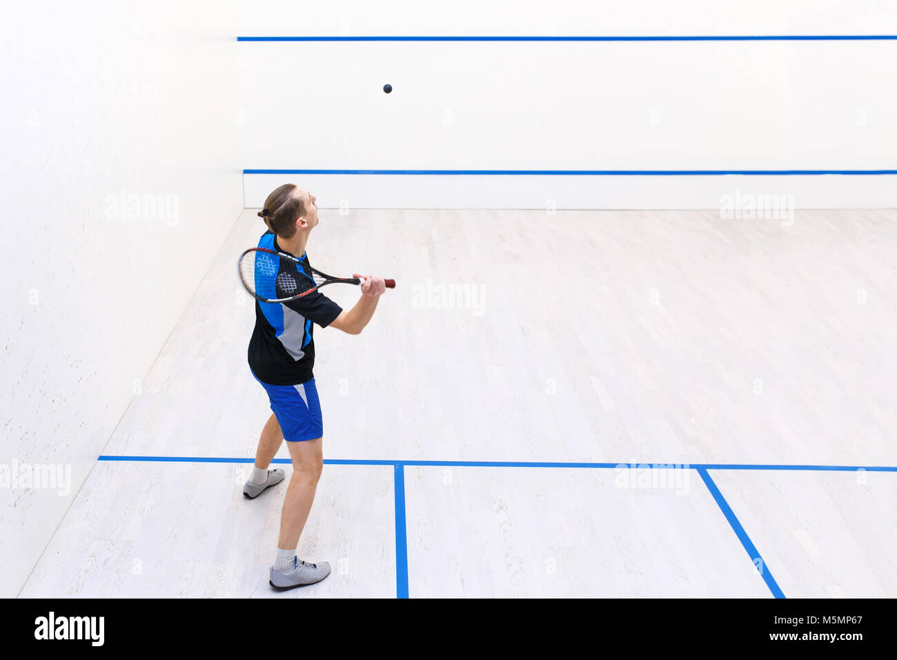 Rückansicht des Squash Spieler Schlagen einer Kugel in einem Squashplatz. Squash Player in Aktion. Mann spielt die Übereinstimmung von Squash. Kopieren Sie Platz. Sport, Menschen, recreat Stockfoto