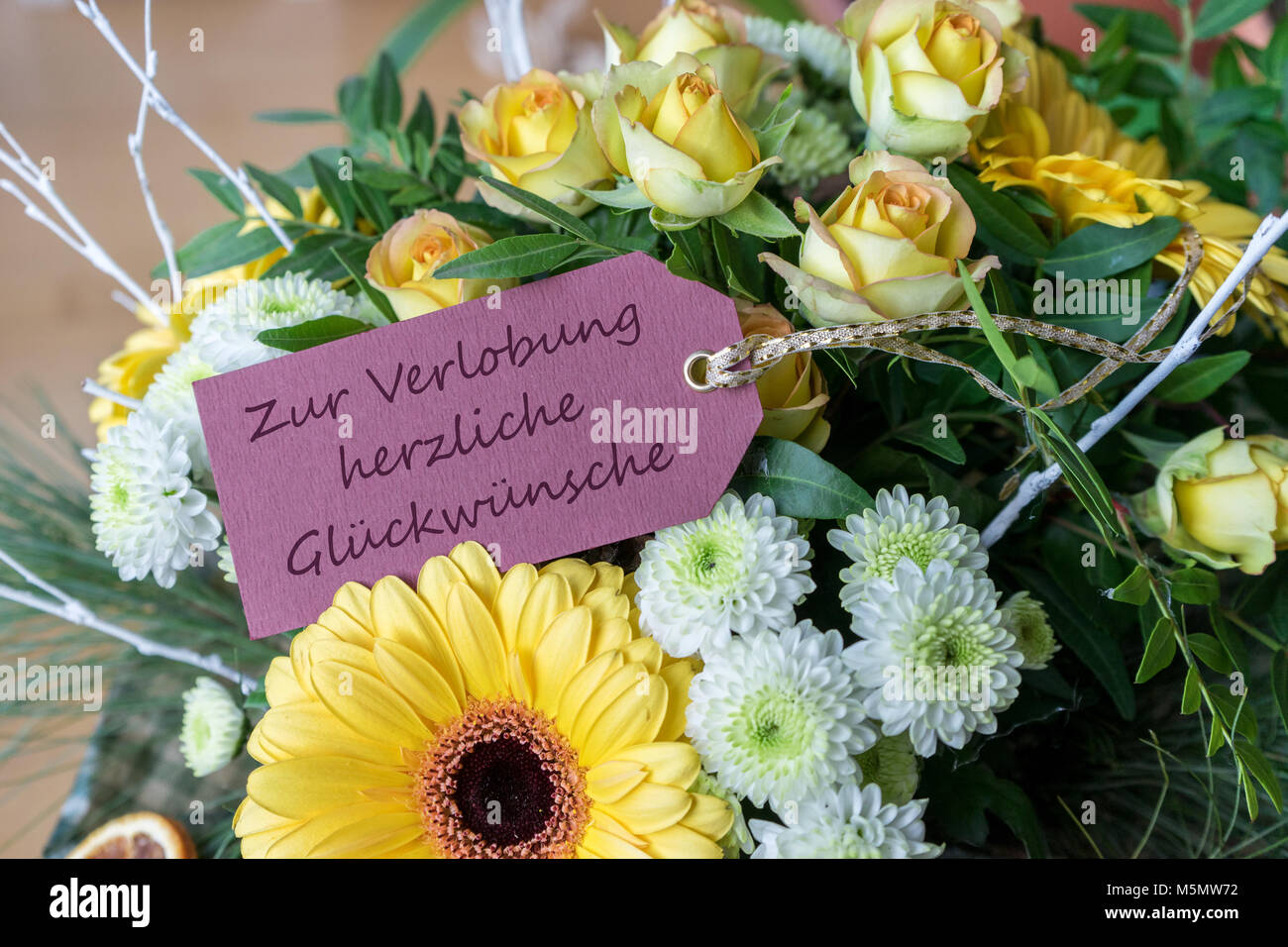 Grußkarte für die Verlobung mit einem Blumenstrauß aus gelben und weißen Rosen, Gerberas, Chrysanthemen und deutschem Text: Herzlichen Glückwunsch zum Engagement Stockfoto