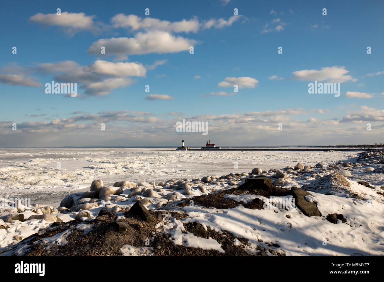 Frozen Lake Superior Küstenlinie mit Leuchttürmen und Schiffsanlegestelle in Duluth, Minnesota, USA im Winter. Stockfoto