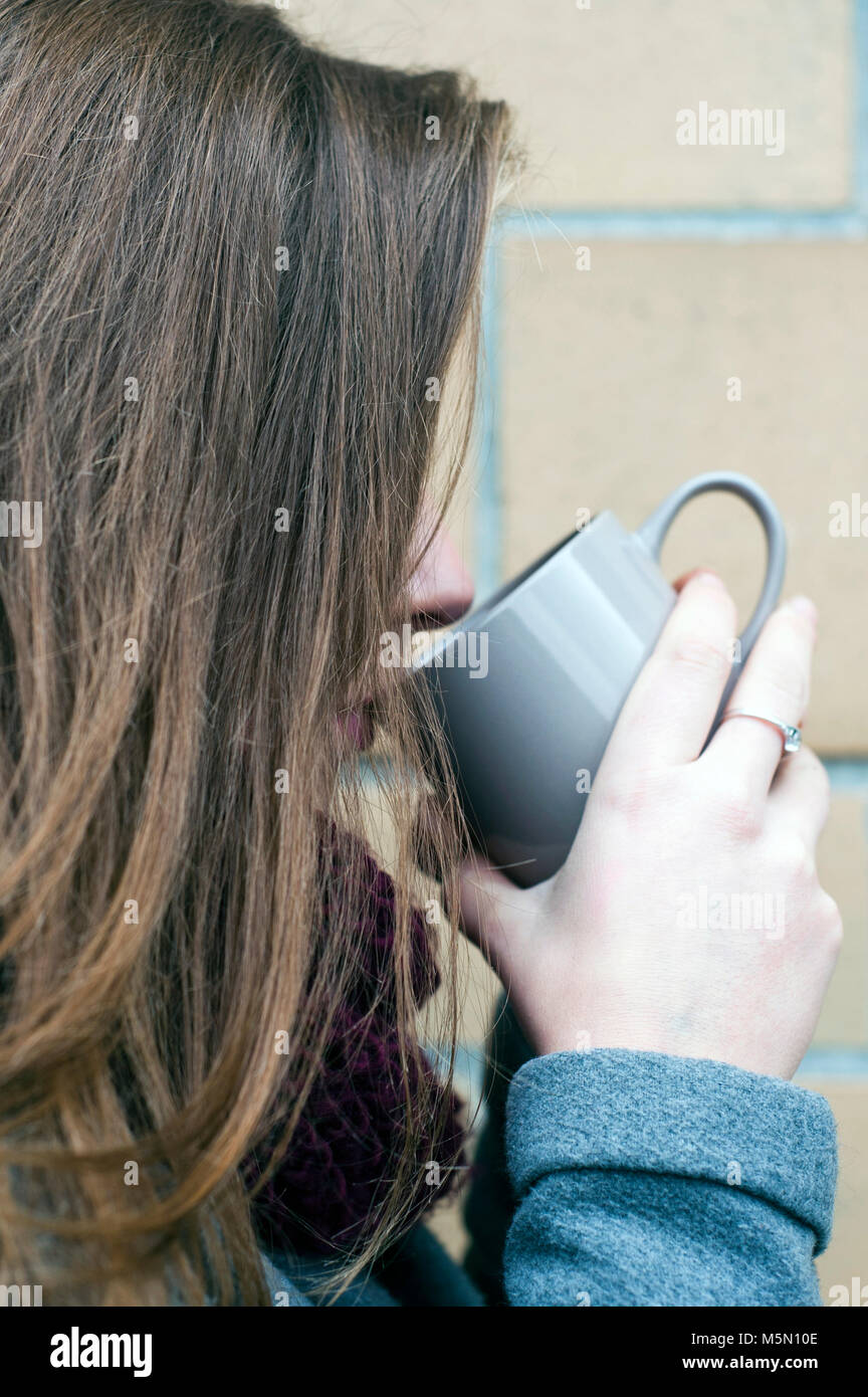 Brünette junge Frau das Trinken aus einem Becher Stockfoto