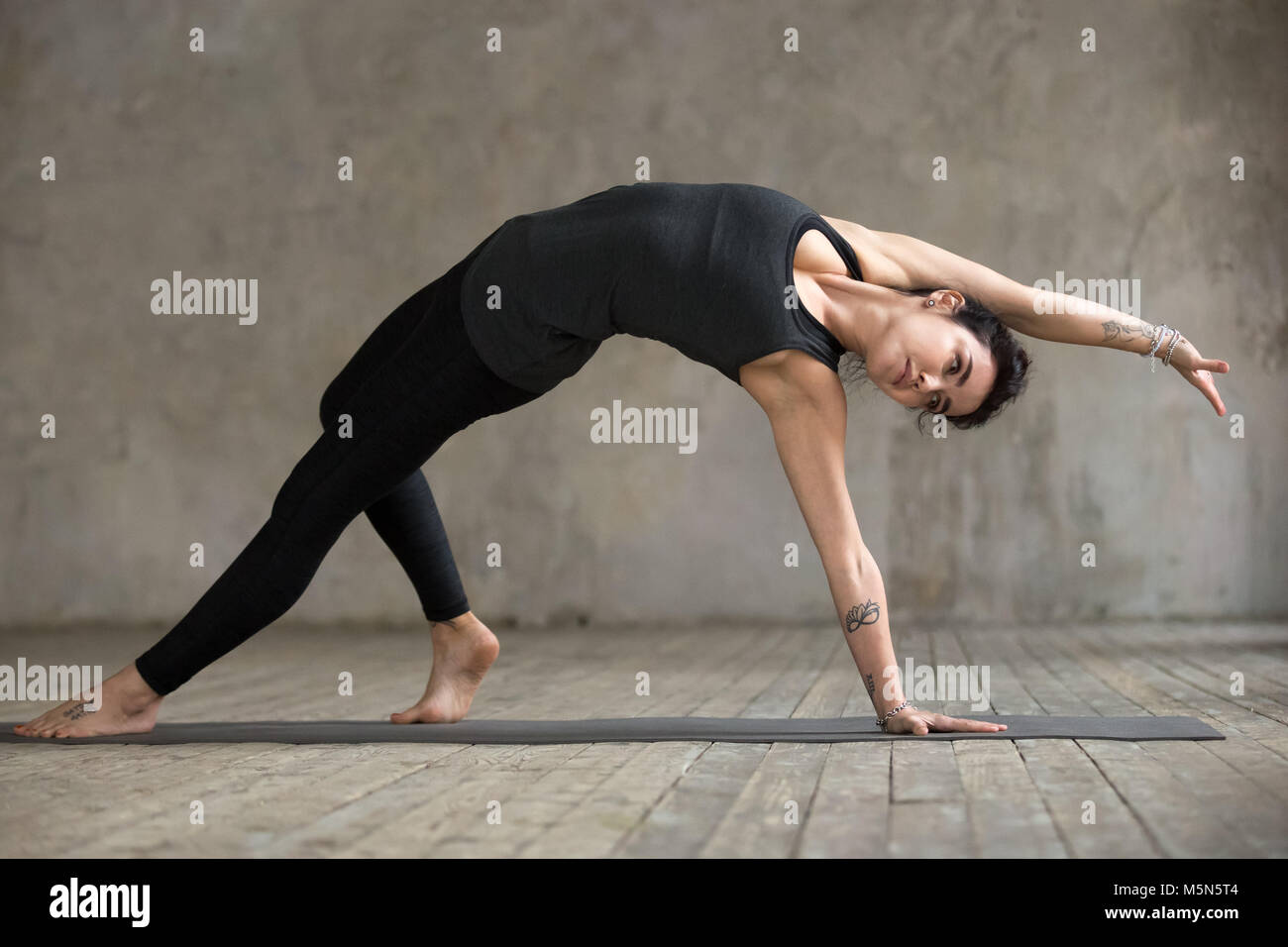 Junge Frau Üben Yoga, wilde Sache, Flip-der-Hund trainieren, Camatkarasana darstellen, arbeiten, tragen Sportswear, schwarze Hose und Top, innen Stockfoto