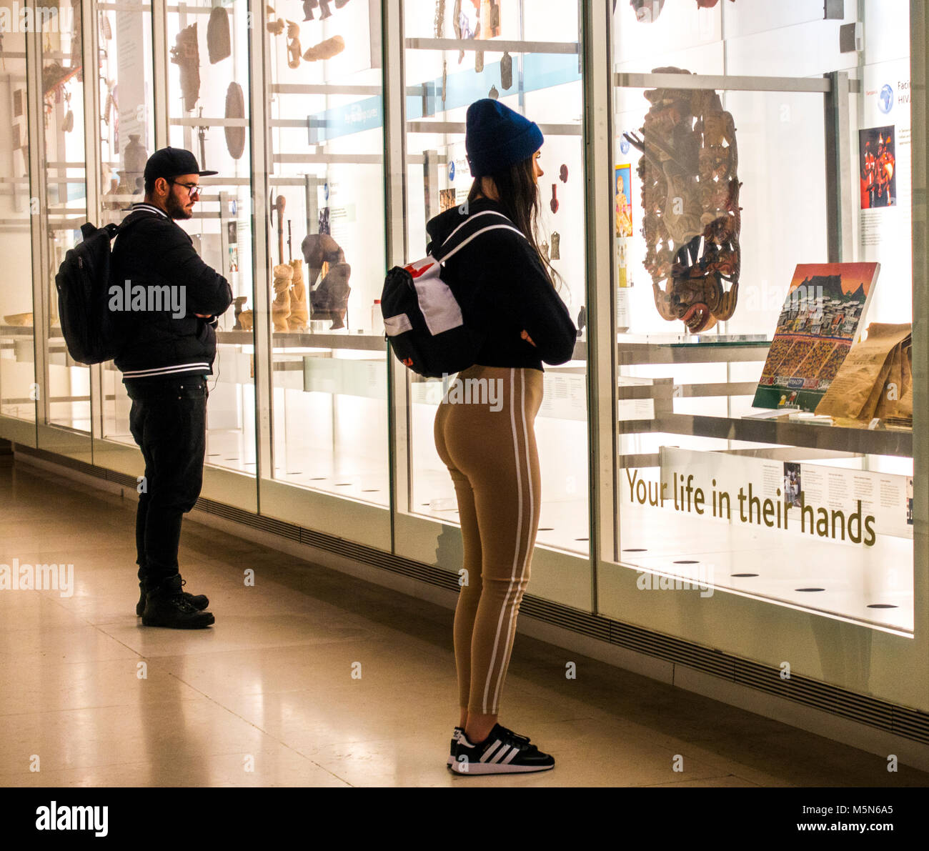 Junger Mann und Frau anzeigen historische Artefakte durch Glas am Britischen Museum (für die menschliche Geschichte, Kunst und Kultur). London, England, UK. Stockfoto