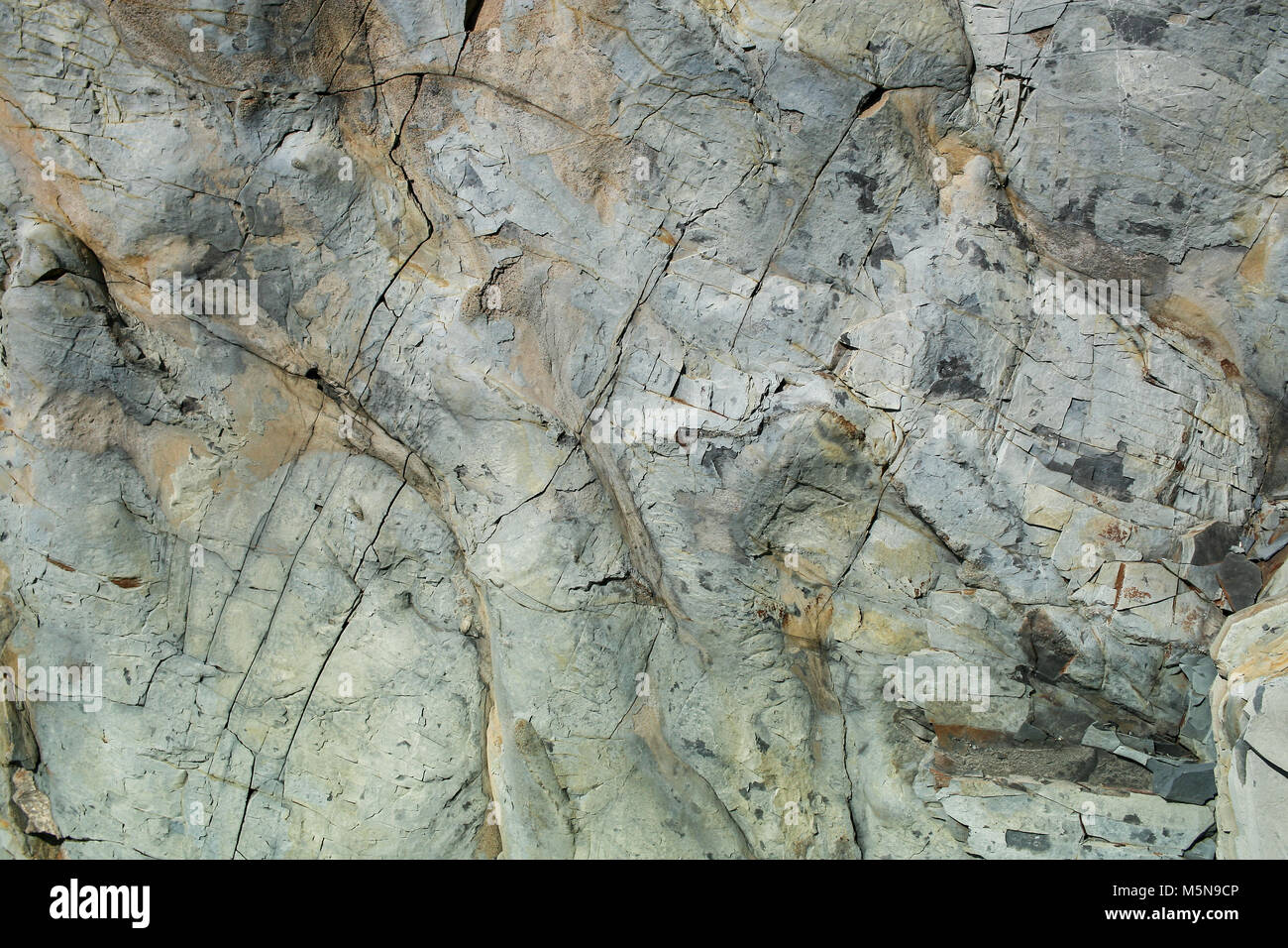 Naturstein grunge grau-braun unebene Wand mit Rissen. Stockfoto