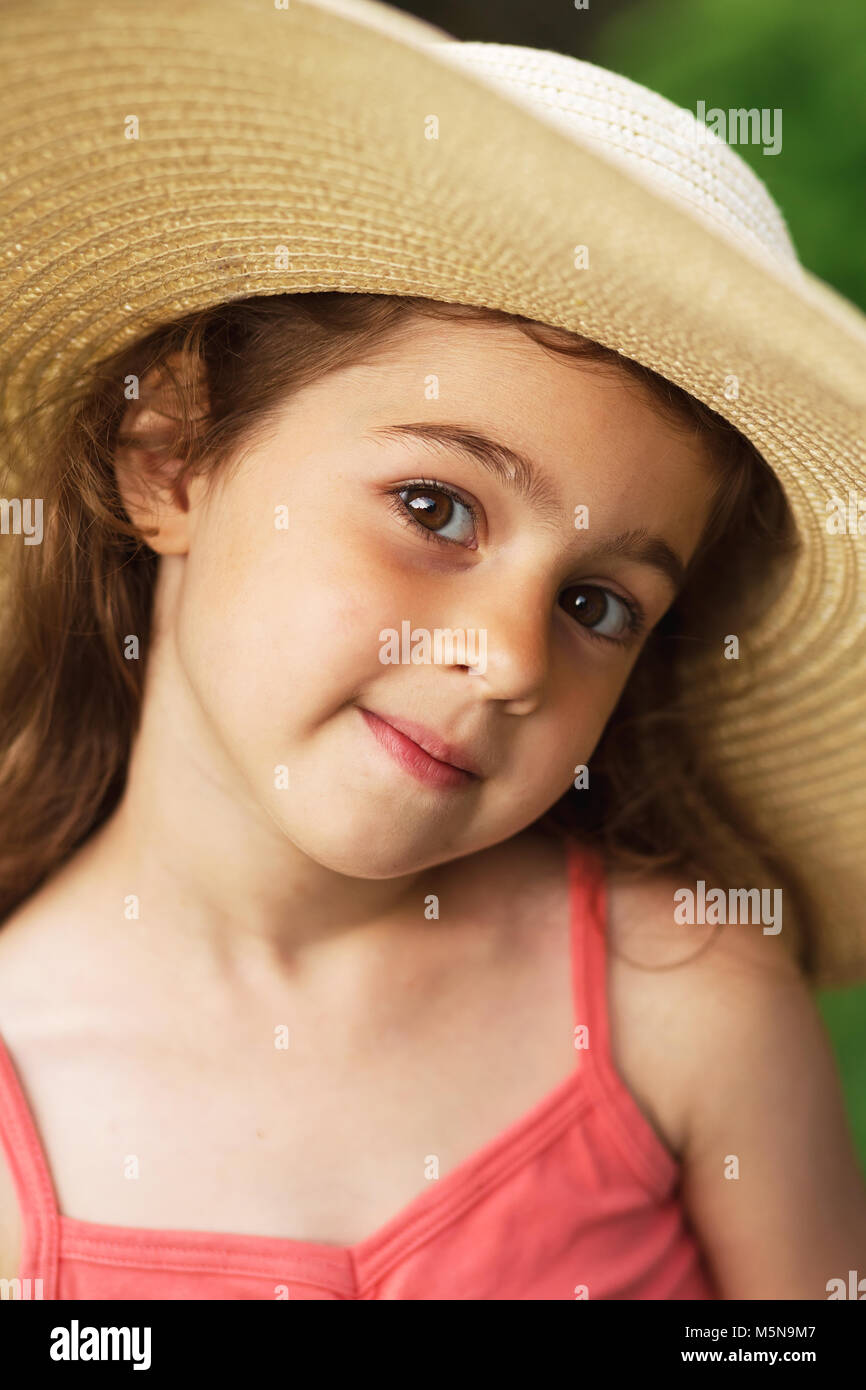 Portrait von lächelnden schönen Kleinkind in Hut mit breiter Krempe am Grün des Sommers Park. Stockfoto