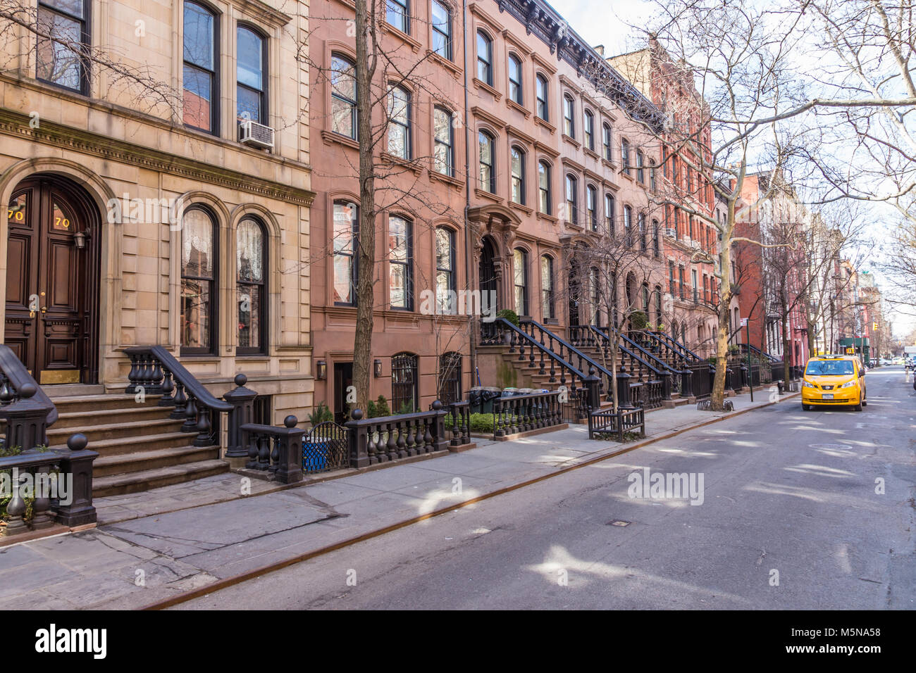 Malerische, von Bäumen gesäumten Straße der historischen Sandsteinhaus Gebäude im Stadtteil West Village von Manhattan in New York City NYC USA Stockfoto