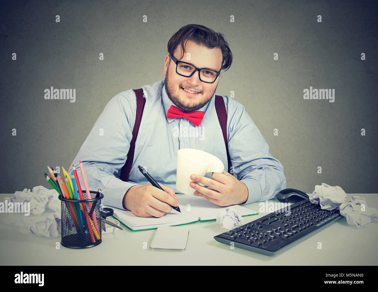 Junge happy business Mann an Schreibtisch mit Papieren beschäftigt und lächelnd an der Kamera sitzt. Stockfoto