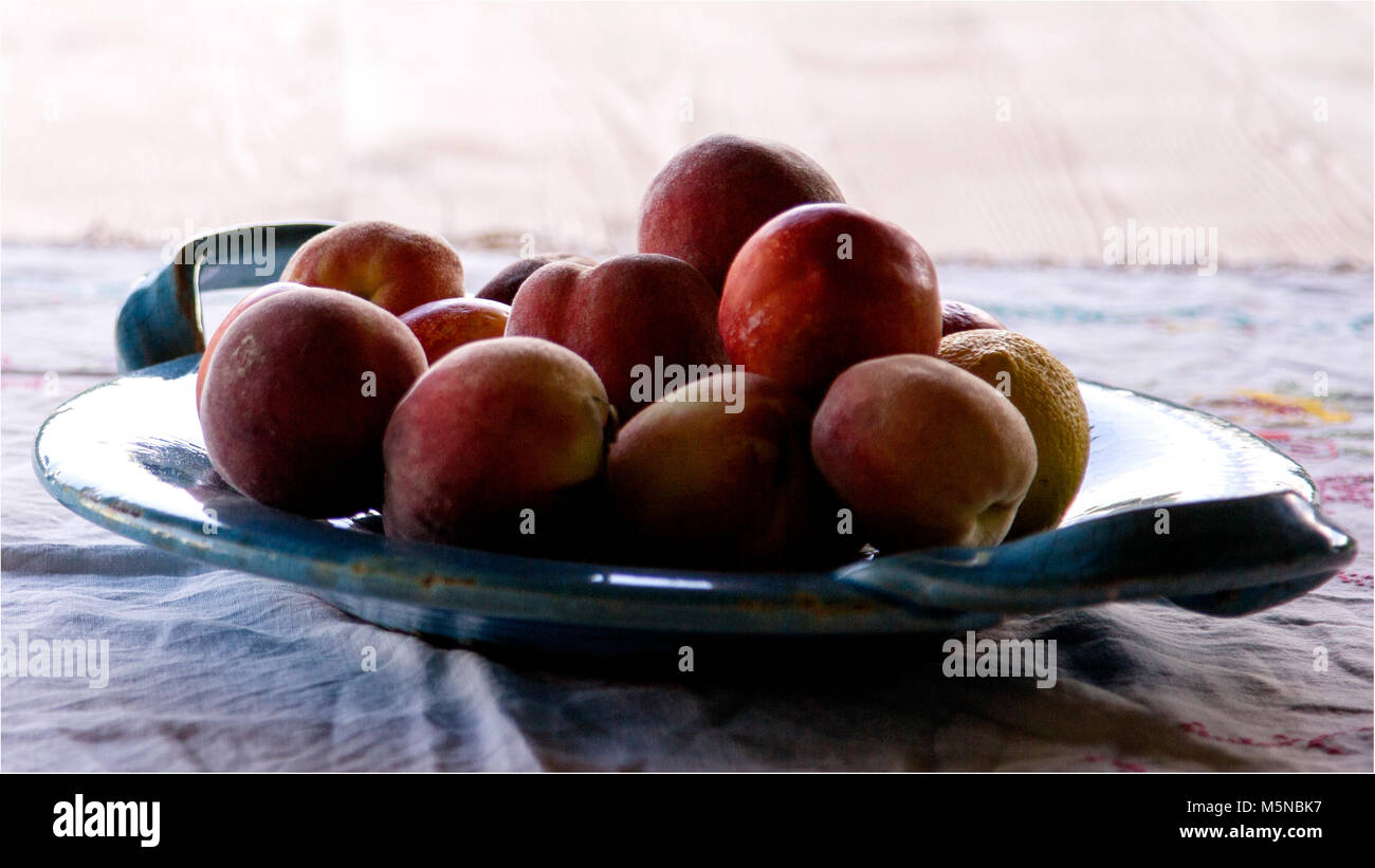Obst, Pfirsiche, Nektarinen und Zitronen auf einem türkis Platter serviert, perfekt für den Sommer, Patio Dining, Frühling feiern oder Tabelle Einstellungen Stück center Stockfoto