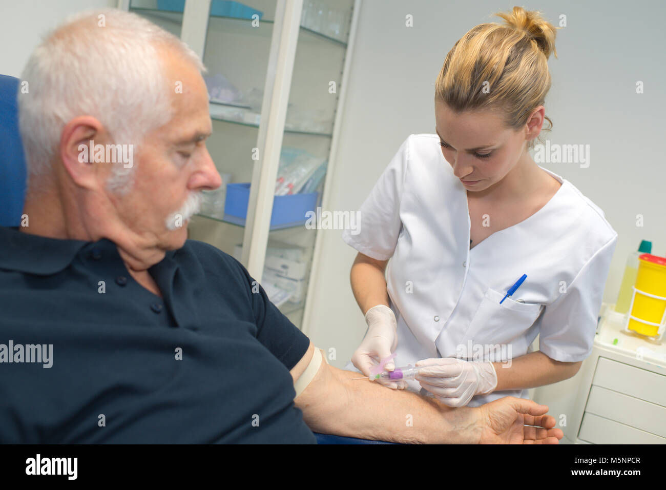 Krankenschwester Zeichnung Blutprobe von älteren männlichen Patienten Stockfoto