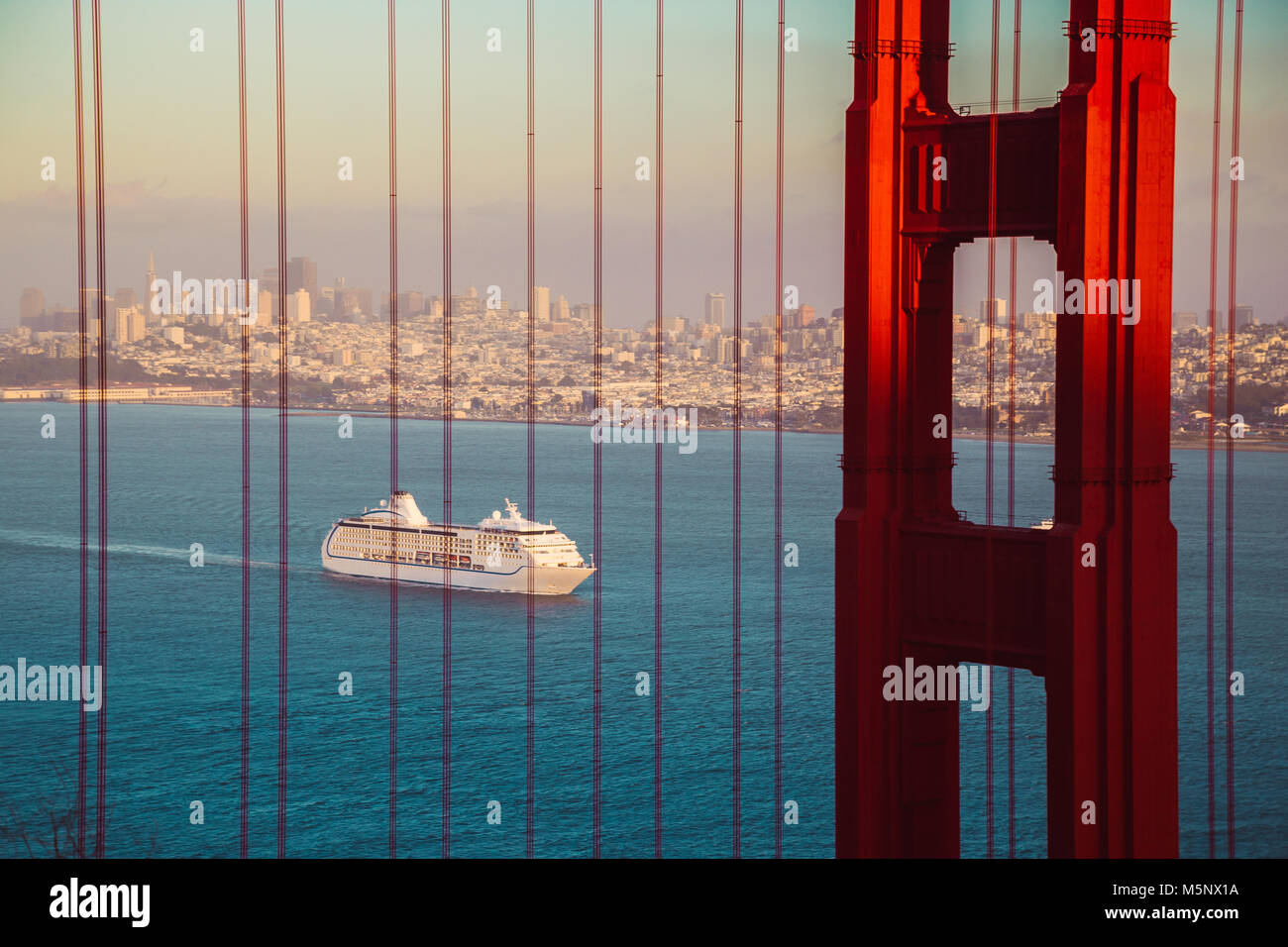 Kreuzfahrtschiff an der berühmten Golden Gate Bridge mit Blick auf die Skyline von San Francisco im Hintergrund im goldenen Abendlicht bei Sonnenuntergang, Kalifornien, USA Stockfoto