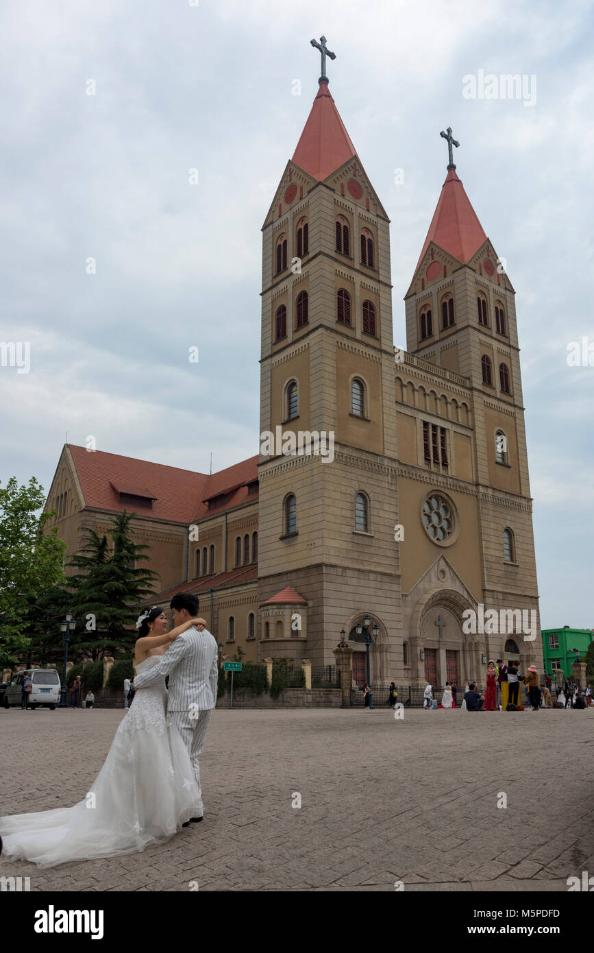 Ein chinesisches Ehepaar stellt für ihre Hochzeit Fotos an der berühmten St. Michael's Cathedral in Qingdao. Stockfoto