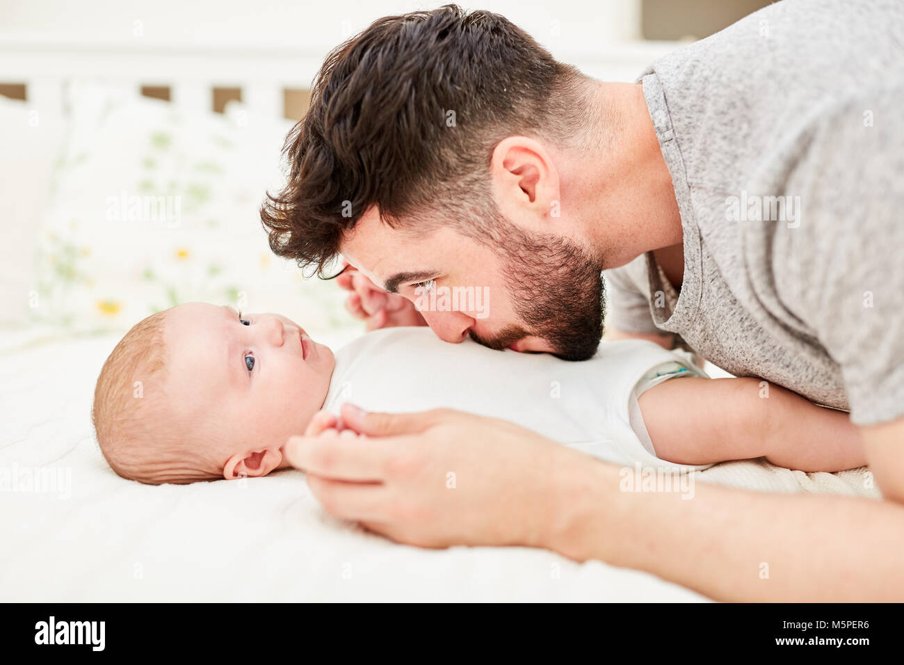 Junger Mann wie ein stolzer Vater liebevoll küsst sein Baby auf dem Bauch Stockfoto