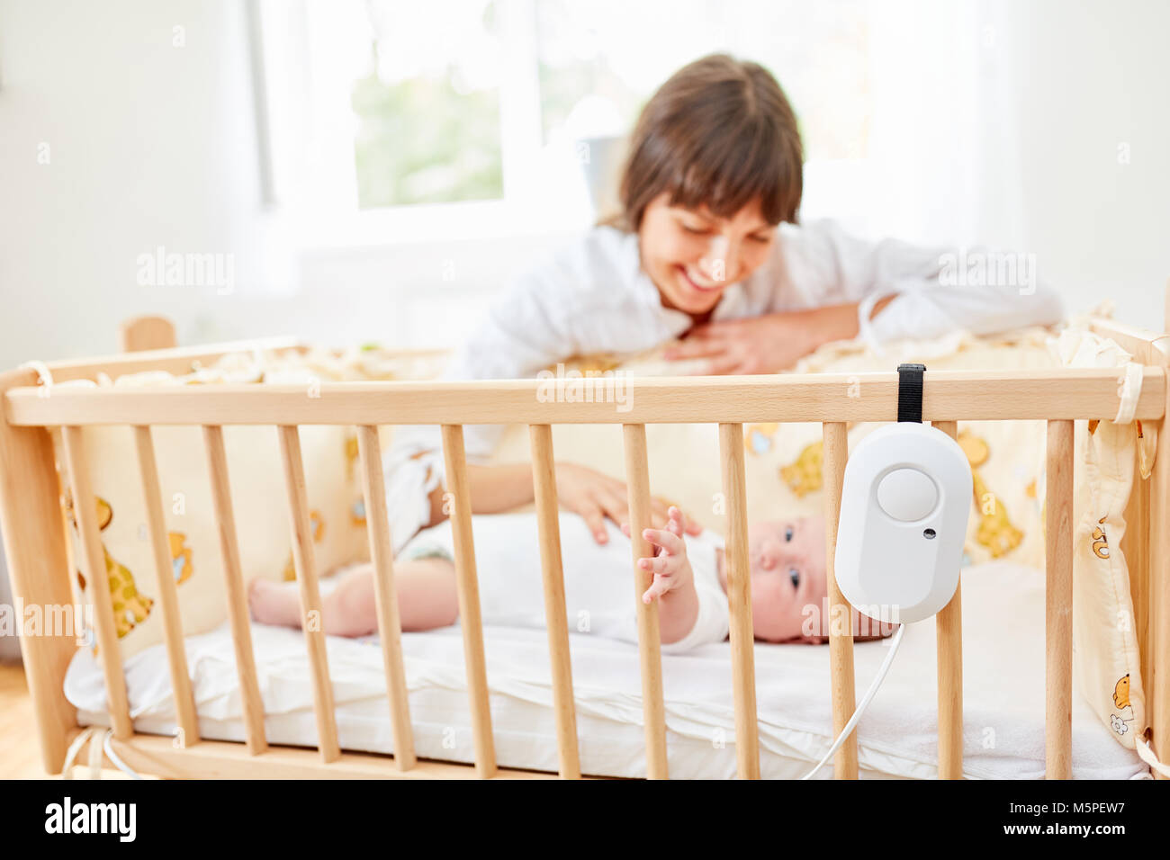 Frau als fürsorgliche Mutter auf dem Kinderbett liebevoll streichelt Kleinkind Stockfoto