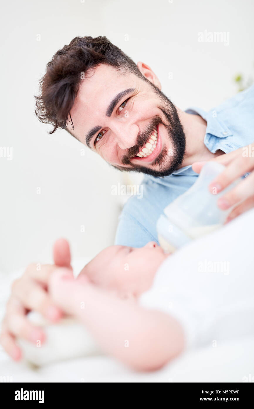 Glücklich Mann als Vater in Elternzeit gibt sein Baby Milch aus der Flasche. Stockfoto
