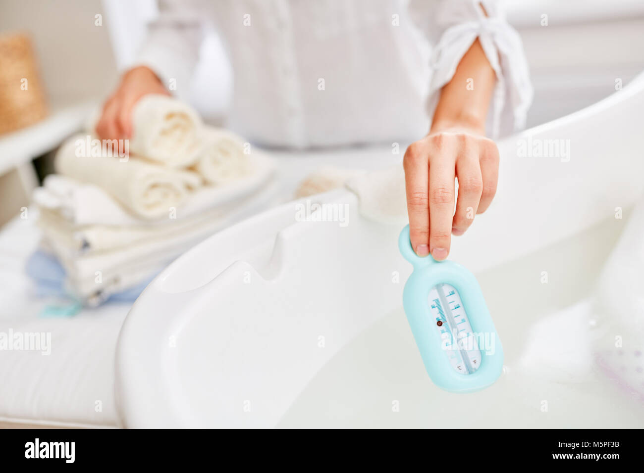 Weibliche hand mit einem Thermometer die Temperatur des Wassers zu messen. Stockfoto
