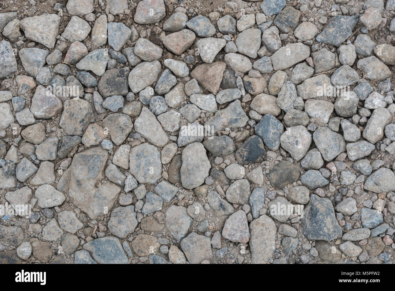 Masse von kleinen Steinen in die Erde abgeflacht. Metapher für „auf steinigen Boden fallen“, felsige Straße, raue Straße voraus. Stockfoto