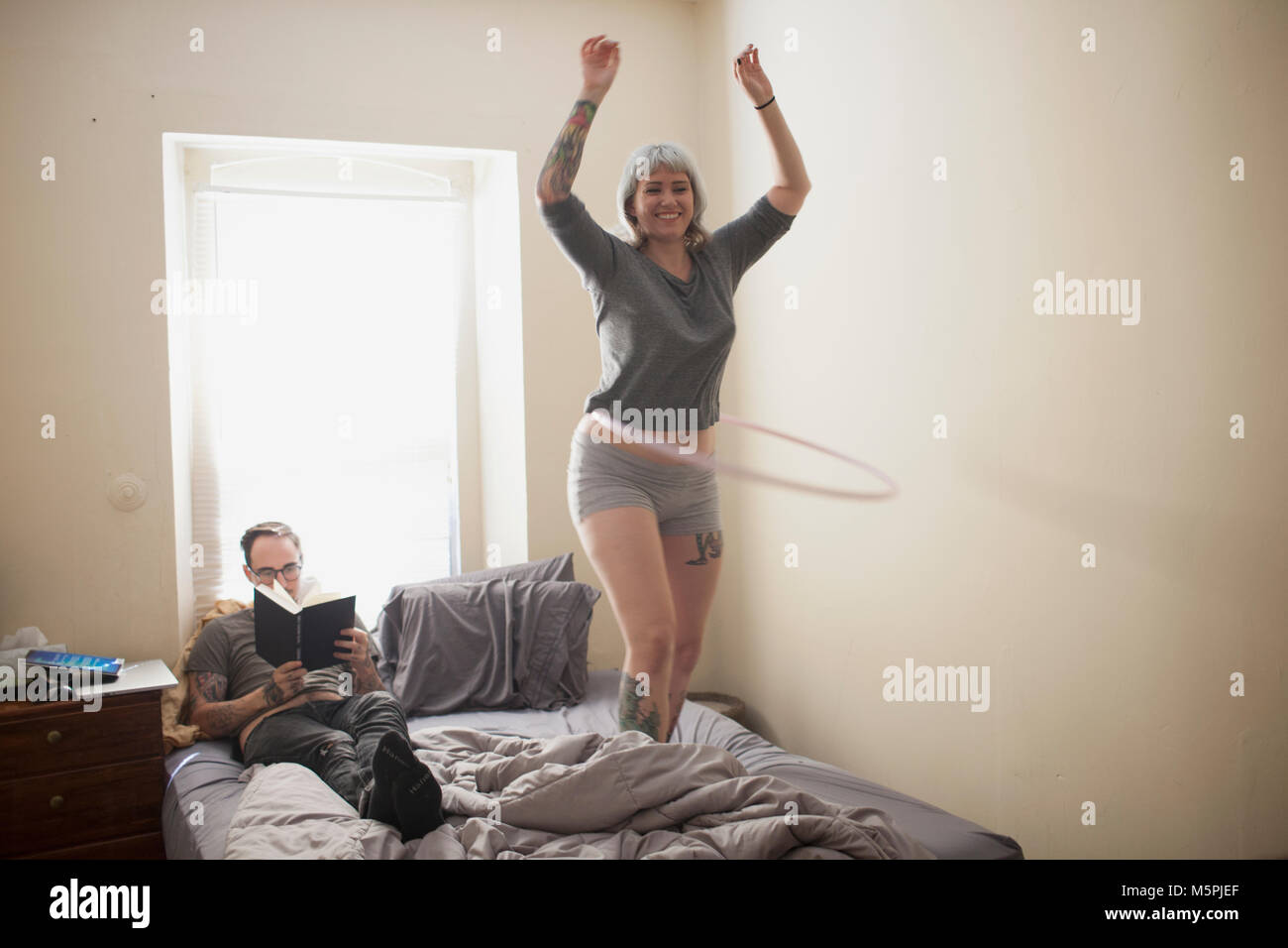 Junge Frau, die auf dem Bett tun, Hula Hoop Stockfoto