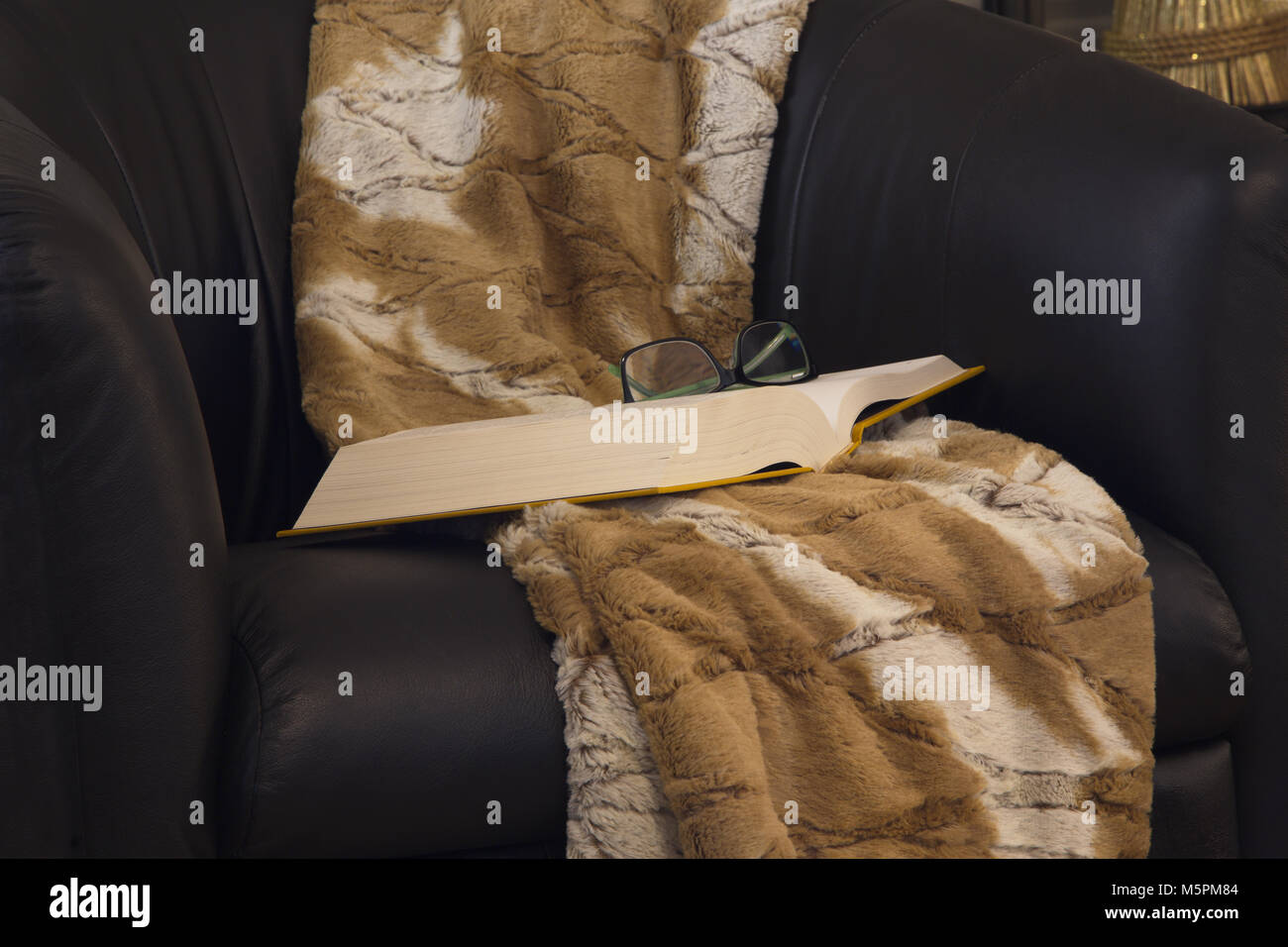 Lässig und authentische Bereitschaft zum Entspannen mit einem guten Buch im Buch öffnen, Brillen wider und gemütliche werfen Decke auf schwarzen Ledersessel. Stockfoto