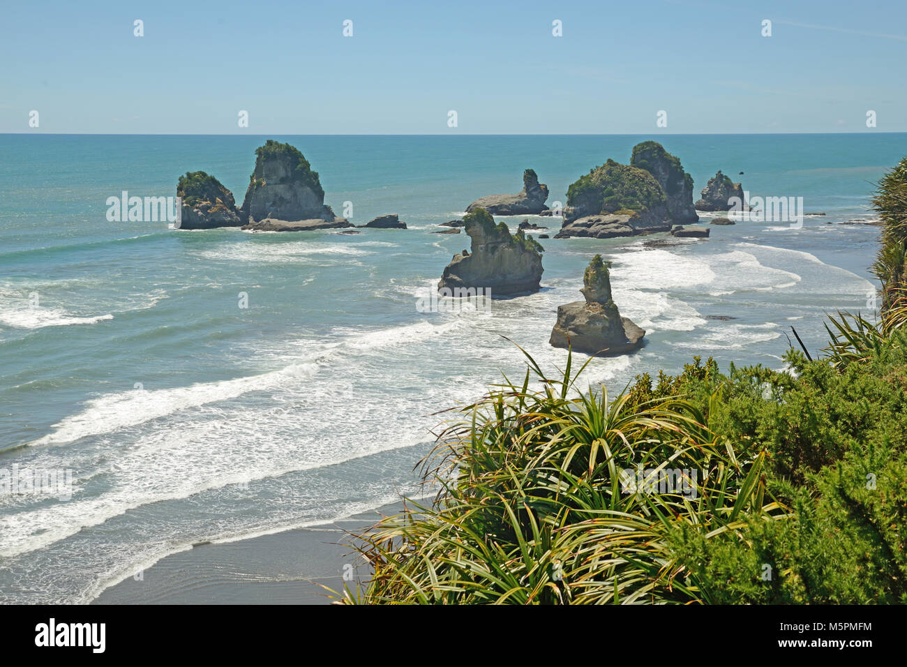 Native Bush Frames ein Strand bei Ebbe auf dem West Coast Beach, South Island, Neuseeland Stockfoto