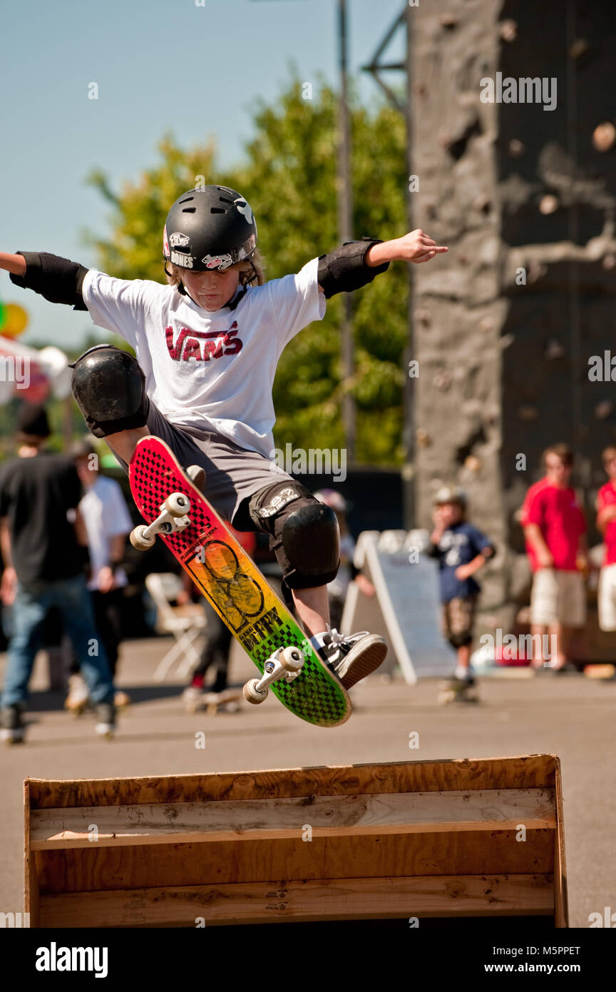 Junge mit Helm auf Skate Board in der Luft über eine Rampe Stockfoto