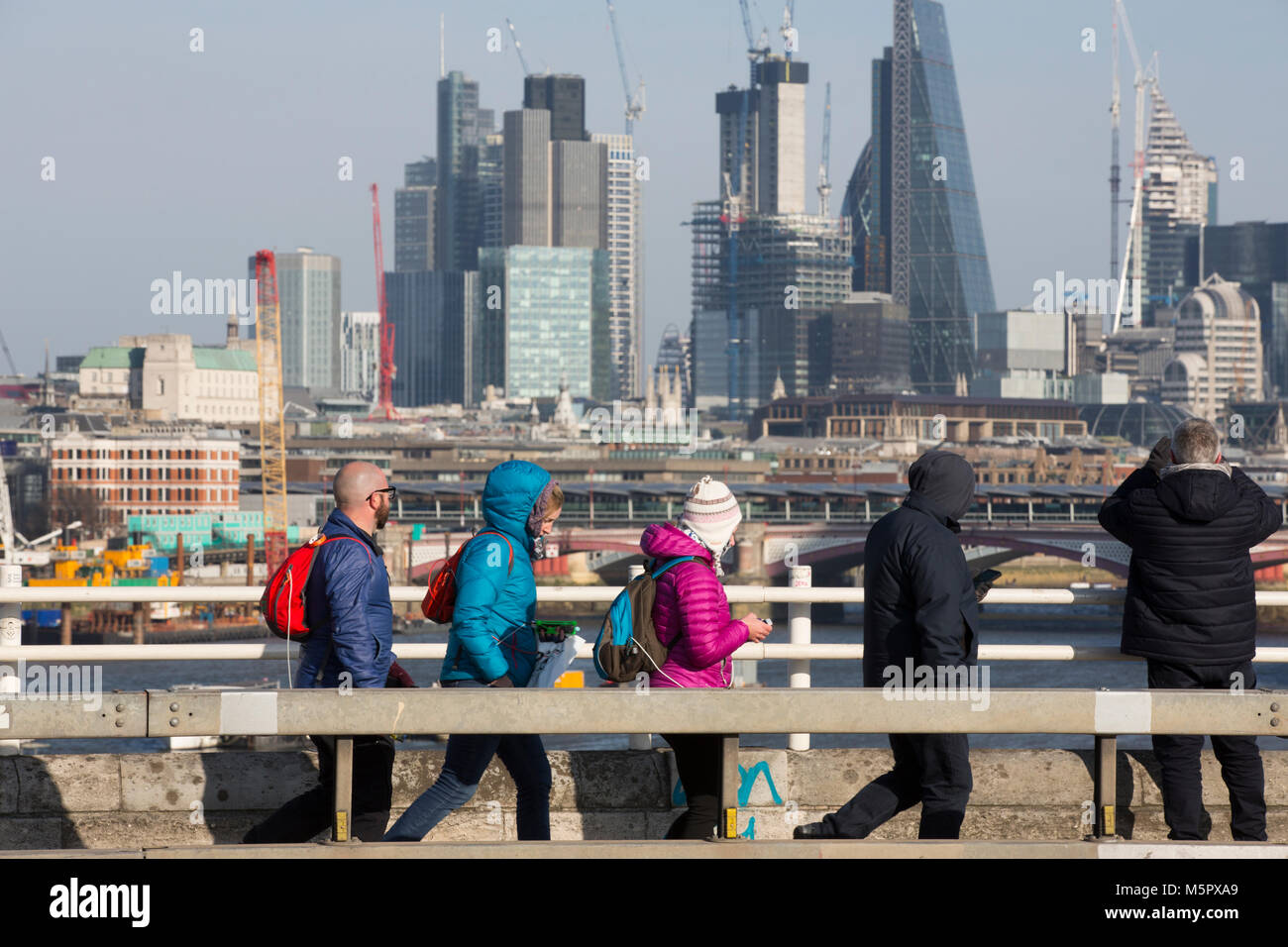 Touristen gekleidet im Winter Kleidung in einer kalten, klaren Tag, stoppen Sie den Blick von der Waterloo Bridge über den Wolkenkratzern der Stadt London, UK zu bewundern. Stockfoto