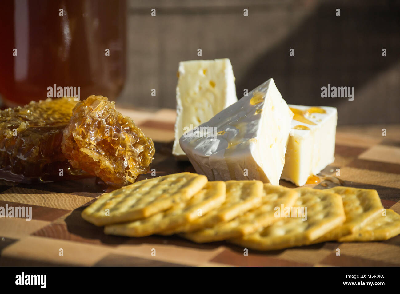 Gourmet gesund Snack-Brie Käse beträufelt mit rohem Honig, mit Crackern, honey comb oder wabe der Seite angezeigt, serviert. Stockfoto