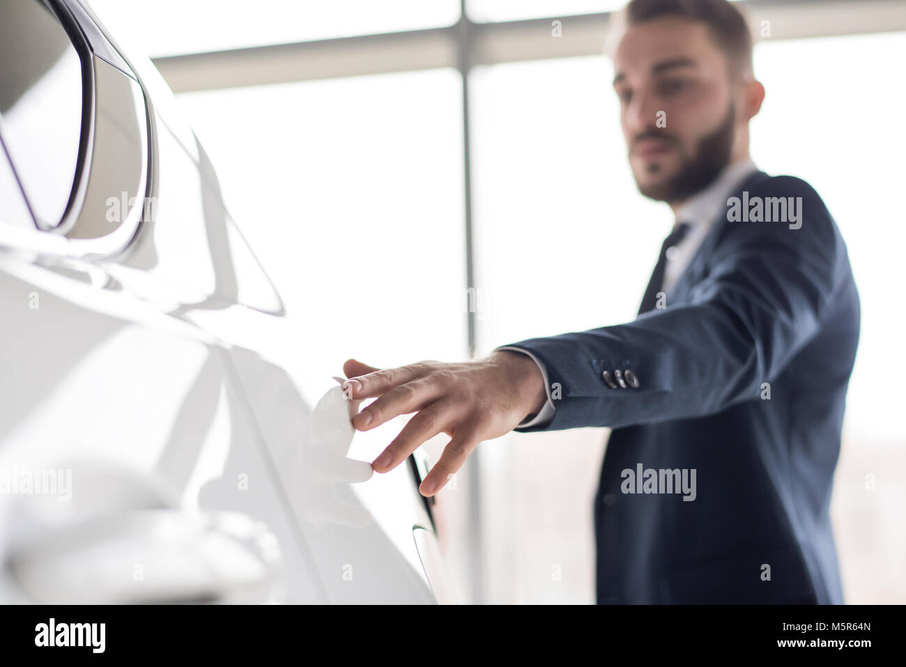 Portrait von stattlichen Geschäftsmann sanft berühren glatten Metall der weißen Luxuswagen, Fokus auf den Vordergrund, kopieren Raum Stockfoto